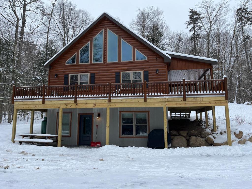 a log cabin with a deck in the snow at Blissful Bear in Old Forge