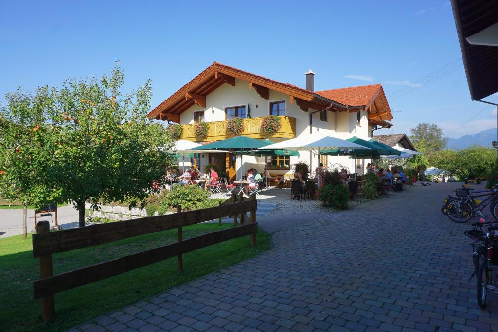 un edificio con mesas y sombrillas en una calle en Cafe Wastelbauerhof - Urlaub auf dem Bauernhof, en Bernau am Chiemsee