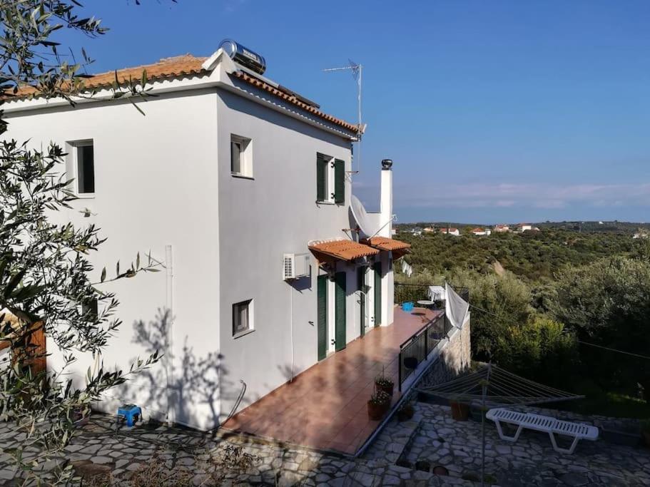 un edificio bianco con una panchina accanto di Haus mit Pool im Olivenhain a Koroni