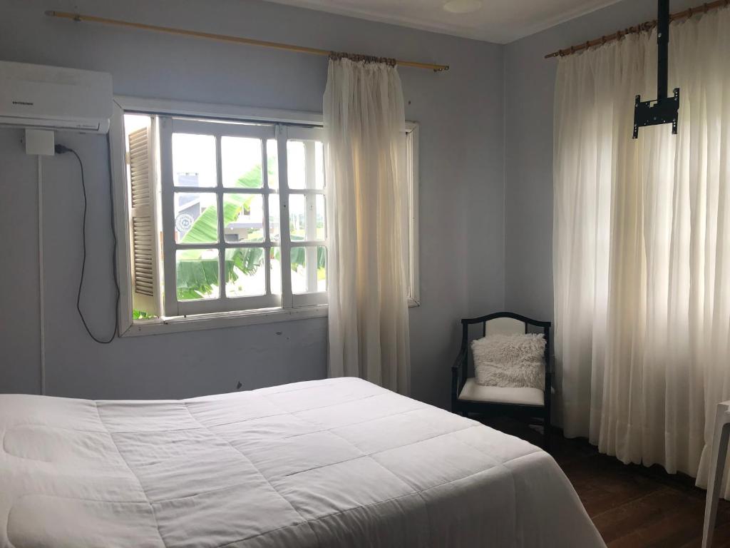 a bedroom with a bed and a window and a chair at Pousada Sossego in São Gabriel