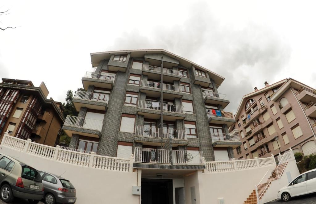 a tall building with cars parked in front of it at Apartaments La Reserva Premium in Noja