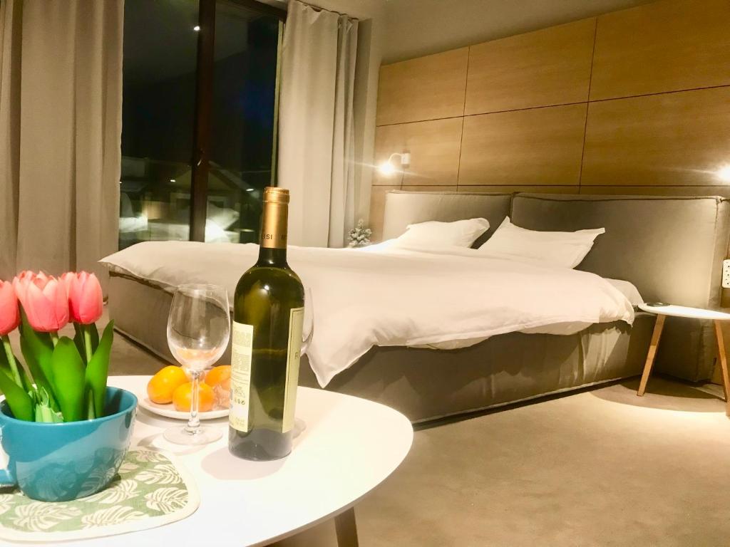 Un dormitorio con una botella de vino y una mesa con flores en New Gudauri Panorama View Loft II en Gudauri