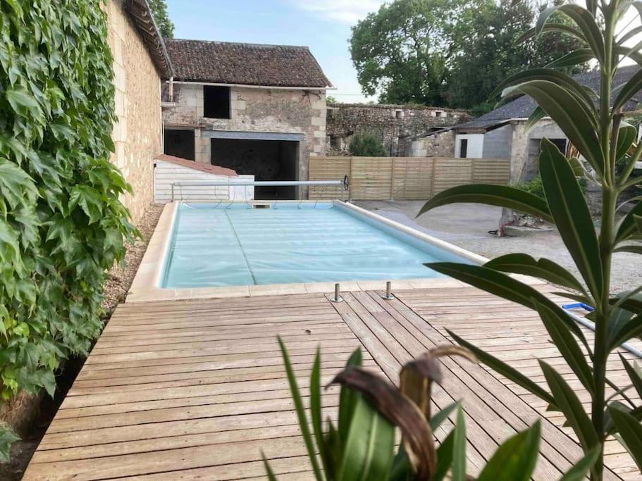 une piscine avec une terrasse en bois à côté d'une maison dans l'établissement Maison 12-14 pers. avec piscine au cœur de la nature, à Vouneuil-sur-Vienne