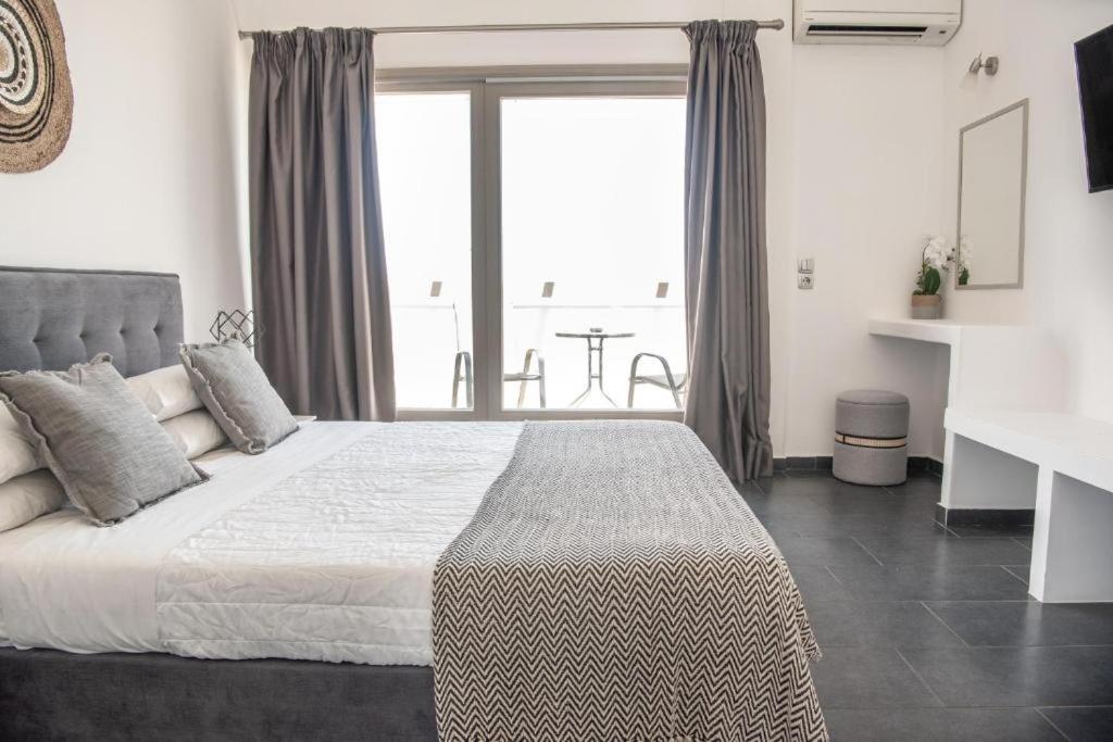 a bedroom with a bed and a large window at AK Suites in Imerovigli
