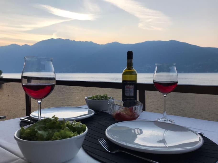 una mesa con dos copas de vino y un tazón de uvas en Exclusive Lakeside Apartment with Amazing View, en Gambarogno
