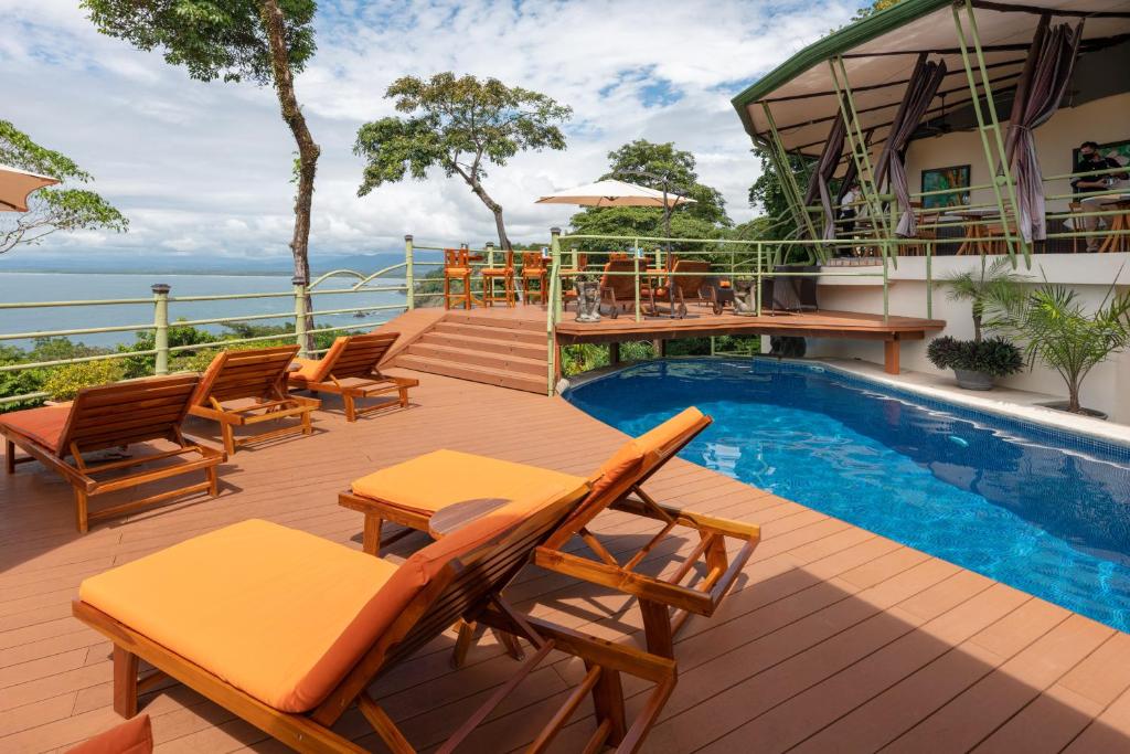 a deck with chairs and a swimming pool at Issimo Suites (Adults Only) in Manuel Antonio
