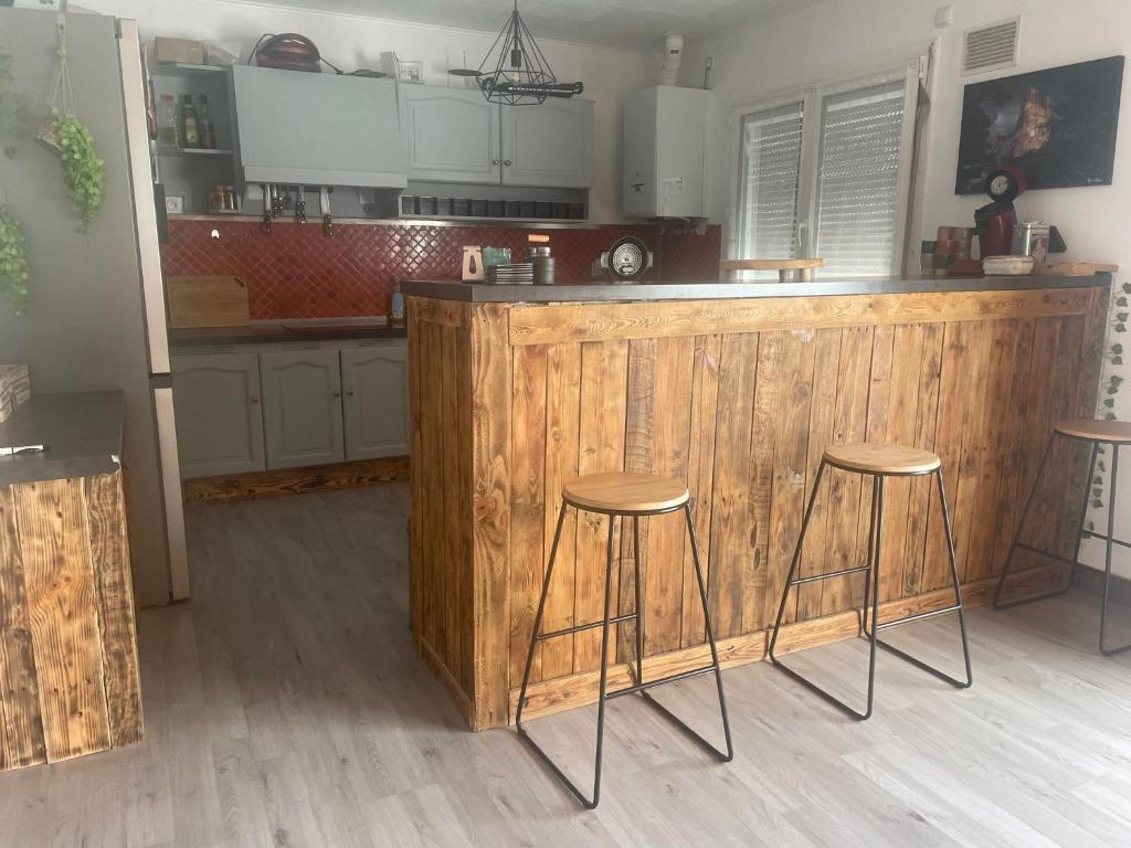 cocina con encimera de madera y 2 taburetes en Le Ranch - proche centre ville, en Reims