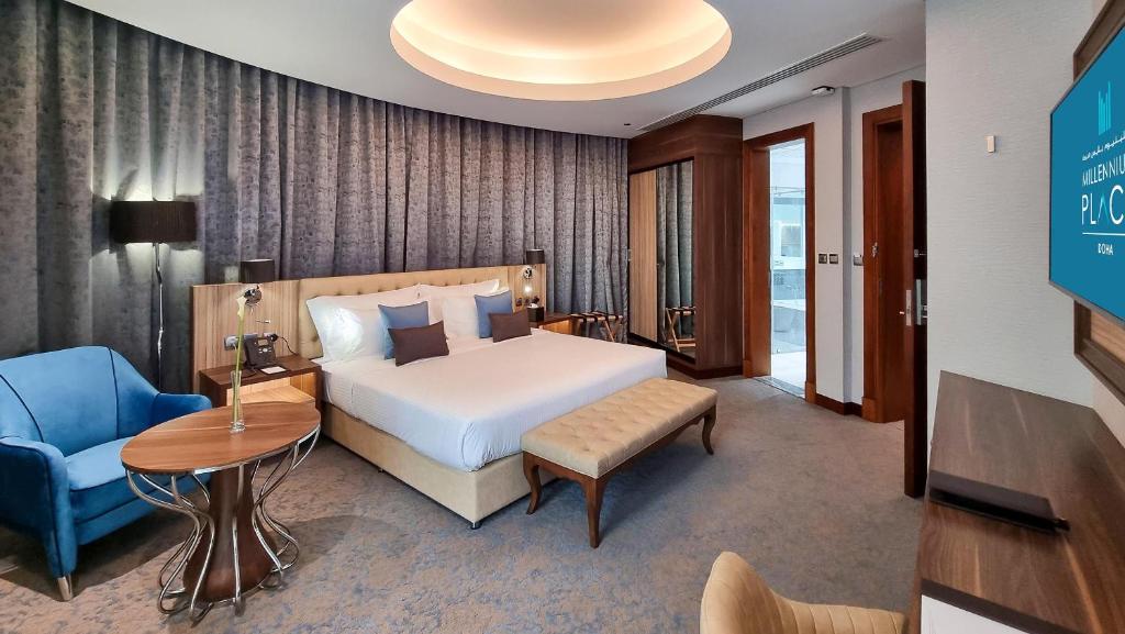 a hotel room with a bed and a blue chair at Millennium Place Doha in Doha