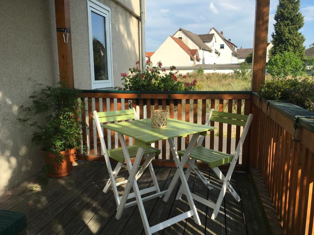 uma mesa verde e duas cadeiras num deque em Charmante Unterkunft ohne Küche in Niestetal bei Kassel em Niestetal