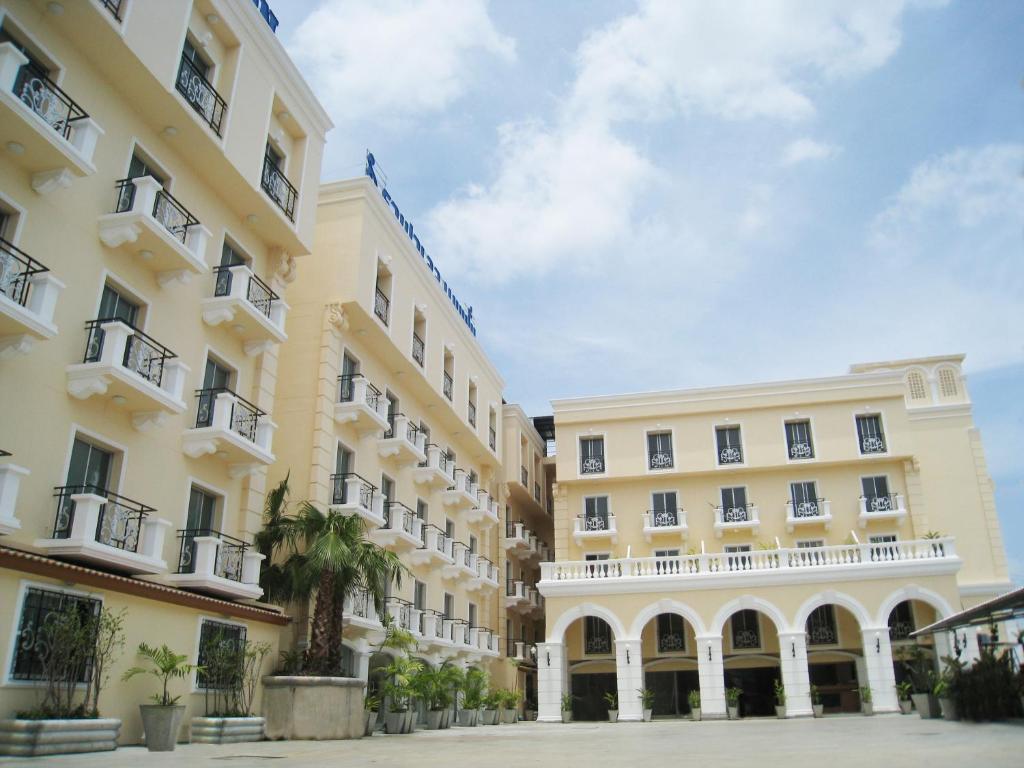 a row of buildings with palm trees in the courtyard at Rafael Hotel and Mansion Bangkok - SHA Extra Plus Certified in Lat Krabang