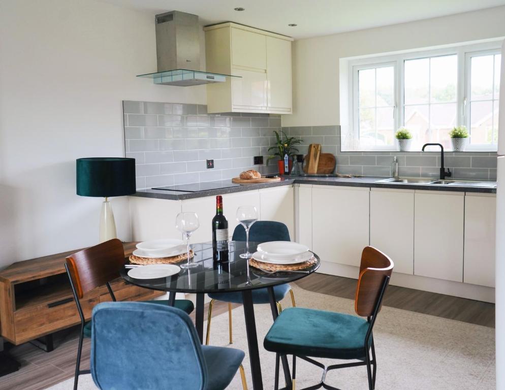 a kitchen with a table with chairs and a bottle of wine at Comfortable and cosy house with off-road parking in Cantley