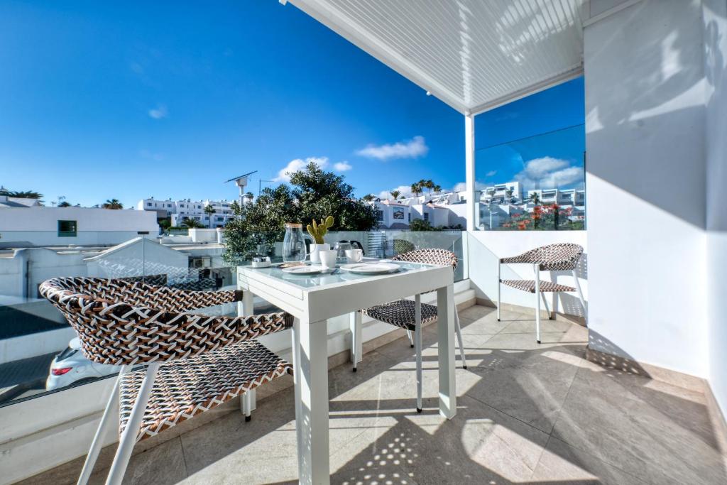 a white table and chairs on a balcony with a view at la Joya Suites- near the beach in Puerto del Carmen