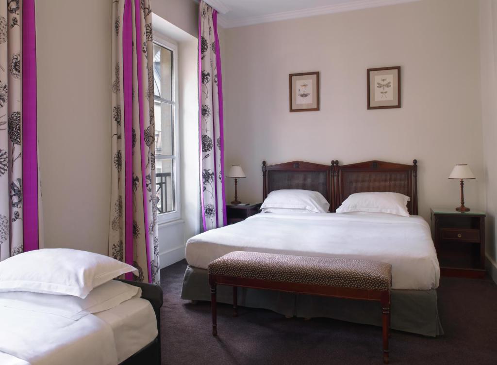 a bedroom with two beds and a window at Hotel Royal Saint Honore Paris Louvre in Paris