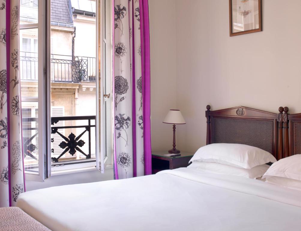 a bedroom with a bed and a large window at Hotel Royal Saint Honore Paris Louvre in Paris