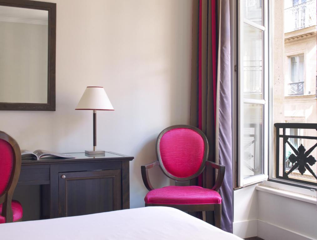 a bedroom with two chairs and a desk and a window at Hotel Royal Saint Honore Paris Louvre in Paris