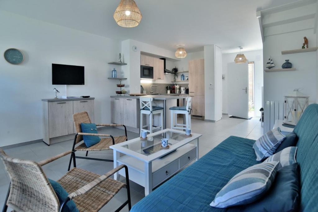 ein Wohnzimmer mit einem blauen Sofa und einem Tisch in der Unterkunft Les Flots de PortMer in Cancale