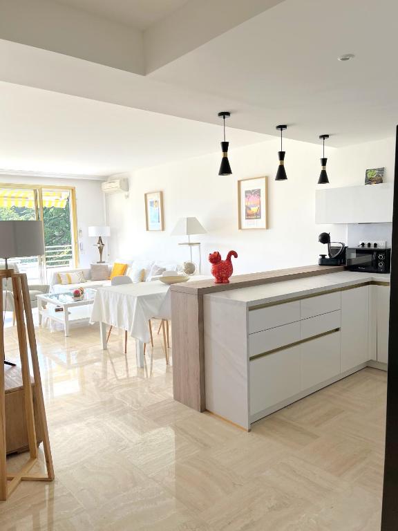une cuisine avec des armoires blanches et un salon dans l'établissement Solezia appartement, piscine et vue mer, by Welcome to Cannes, à Cannes