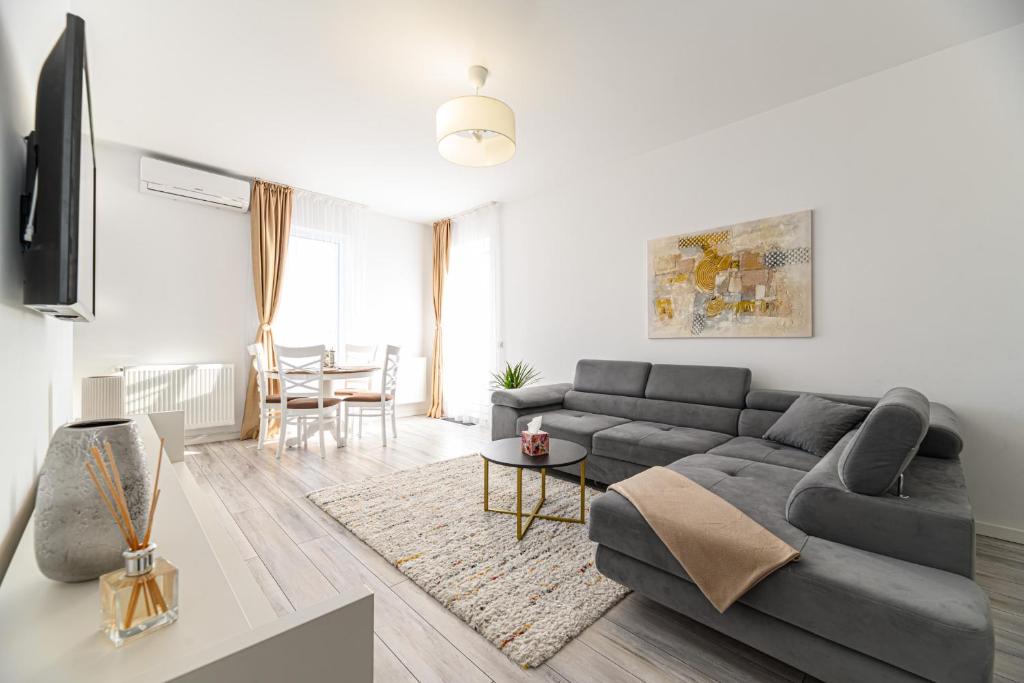 a living room with a gray couch and a table at MaBu Apartment -2 camere spatios cu parcare subterana, Tractorul Brasov in Braşov