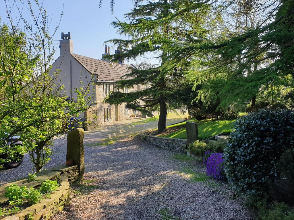 ein Haus mit Bäumen und eine Straße davor in der Unterkunft Sculpture Park Cottage in Penistone