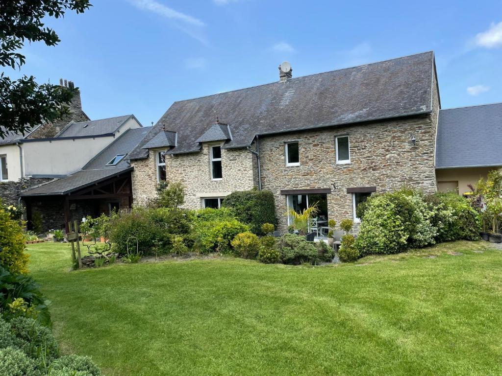 Les Maisons des Halles في Cerisy-la-Forêt: منزل حجري كبير مع ساحة كبيرة