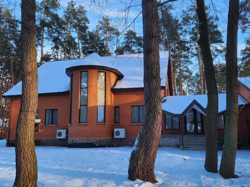 une maison orange dans la neige avec des arbres dans l'établissement Комплекс відпочинку "Пуща-Водиця", à Kiev