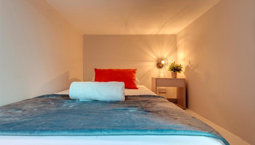 ein Schlafzimmer mit einem Bett mit einem roten Kissen darauf in der Unterkunft DORADO PLAZA GETSEMANI in Cartagena de Indias