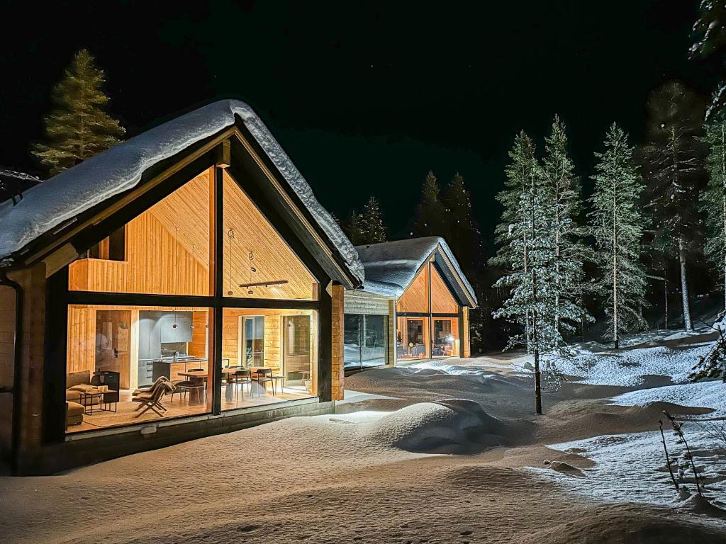 a large wooden house in the snow at night at Kimmelvilla Pyhä - Ski-in, modern design and spectacular scenery in Pyhätunturi