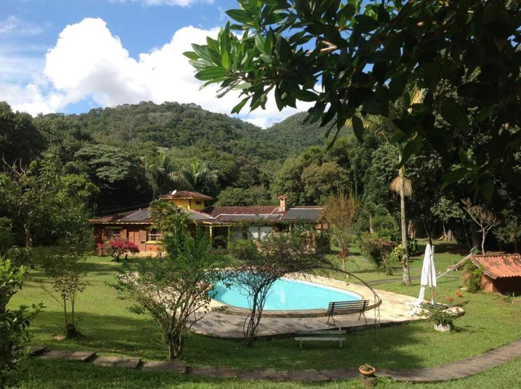 una casa con piscina en un patio en Aldeia Gaia Chalés en Teresópolis