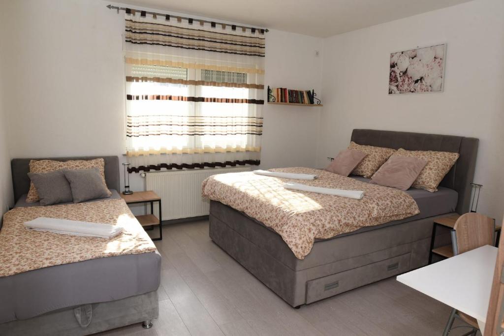 a bedroom with two beds and a window at Apartman Mila in Županja