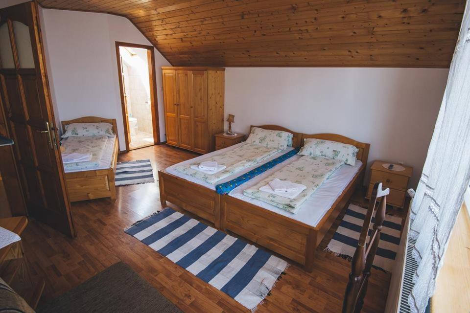 een slaapkamer met 2 bedden en een houten plafond bij Balázs Panzió in Corund