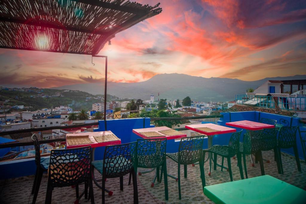 a group of tables and chairs on a balcony with a sunset at Dar Chourafa Riad in Chefchaouen