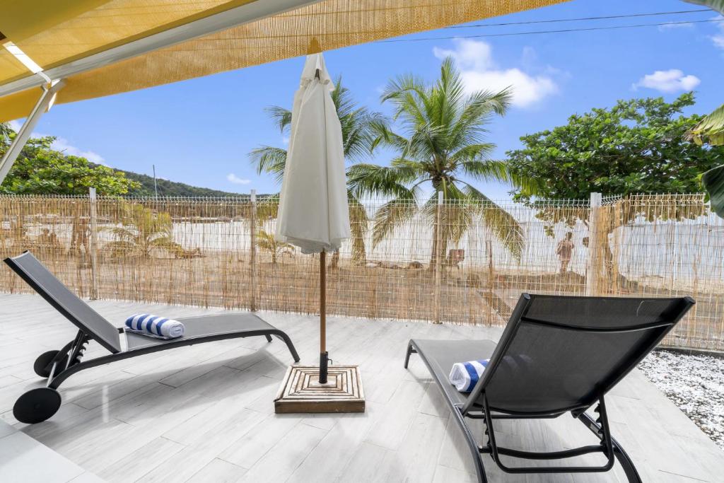 un patio con 2 sillas y una sombrilla en Villa Kaz Kreyol, en Les Anses-dʼArlet