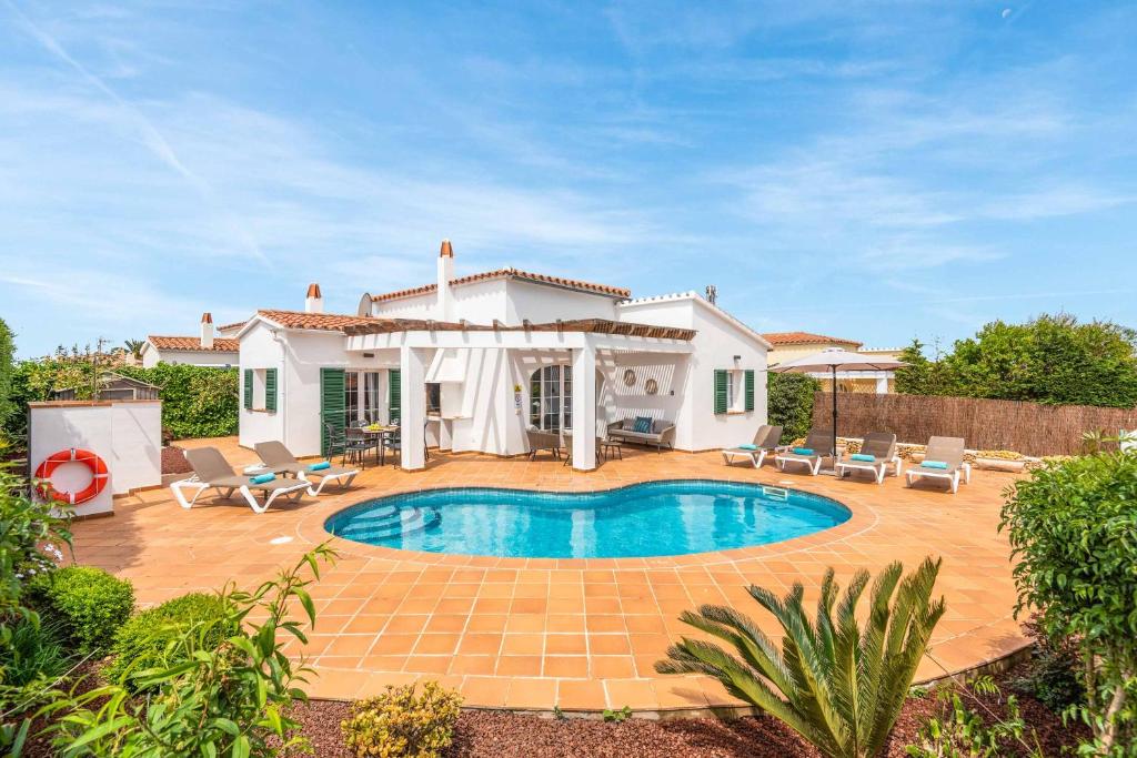 a villa with a swimming pool in front of a house at Villa Sara Porter in Cala en Porter