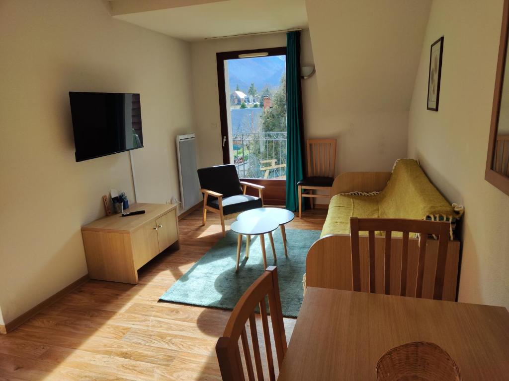 un salon avec une table et un salon avec une télévision dans l'établissement Evasion Pyrénéenne, à Luchon