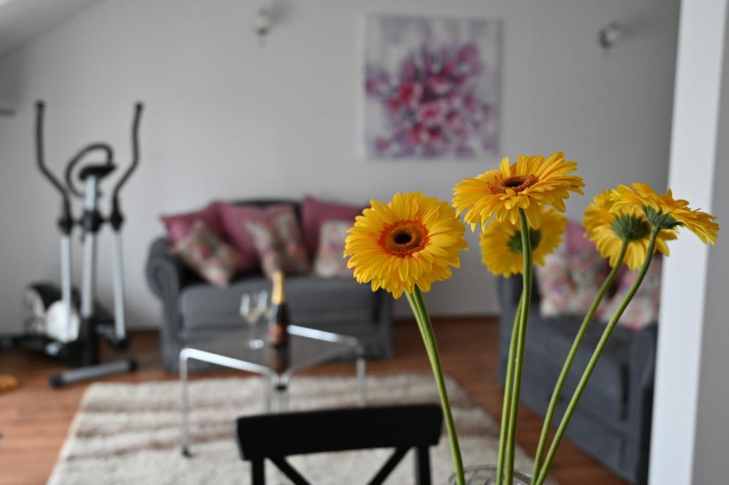 un jarrón con flores amarillas en la sala de estar en Apartmani Lucija en Ludbreg