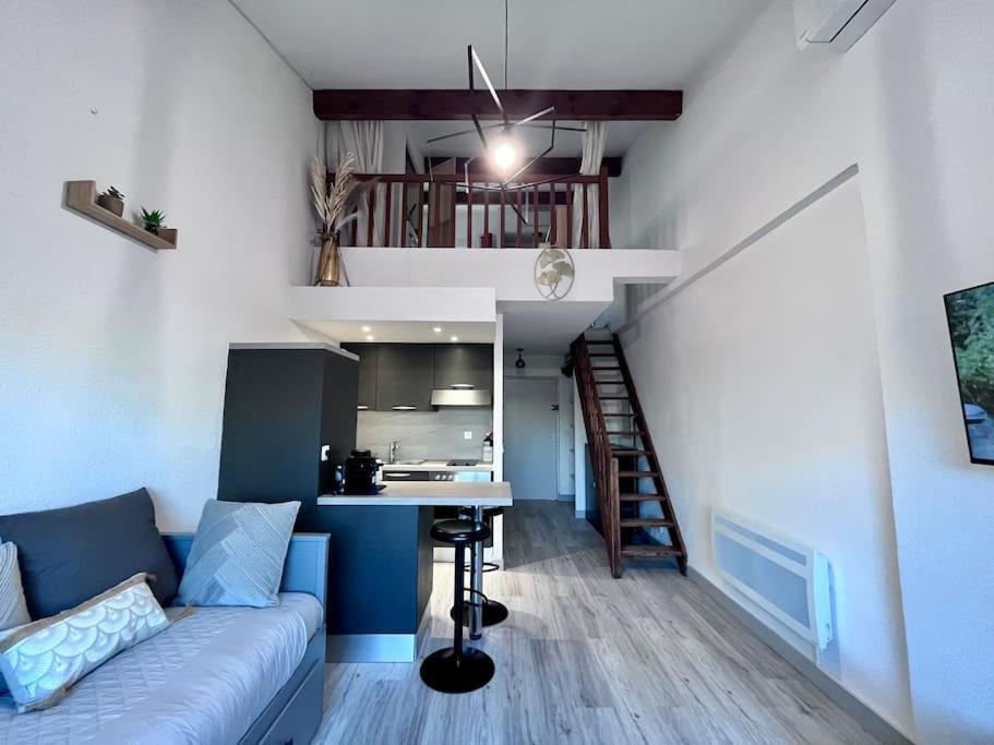 un salon avec un canapé bleu et une cuisine dans l'établissement Magnifique T1bis dans CALVI centre avec Parking, à Calvi