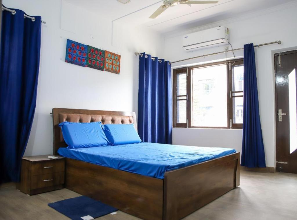 瓦拉納西的住宿－The Kutumb- Holiday Home，一间卧室配有一张带蓝色床单和蓝色窗帘的床。