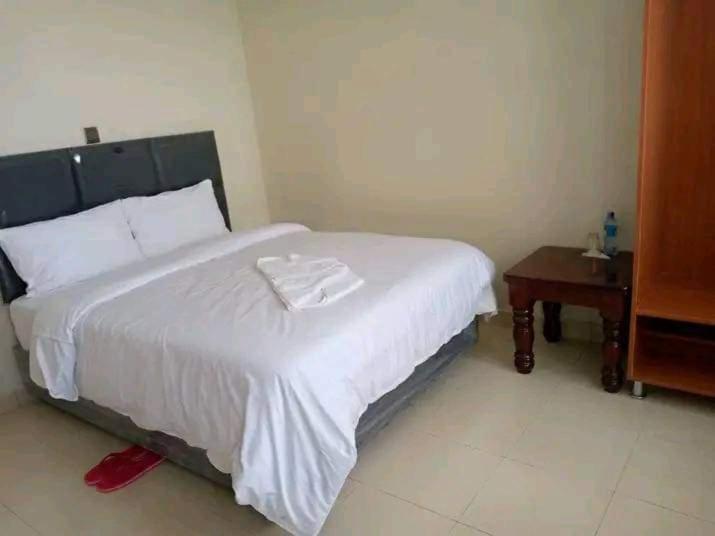 a bedroom with a large white bed and a table at Sagada Resort Lamuria in Nyeri