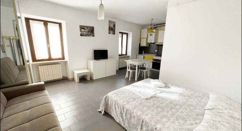 a white bedroom with a bed and a kitchen at La Piazzetta, il centro di Biella in Biella