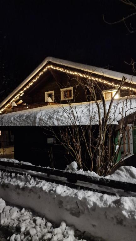 Chalet-Daheim-Fiesch 3,5-Zimmerwohnung في فيش: منزل مغطى بالثلج مع وجود أضواء عليه