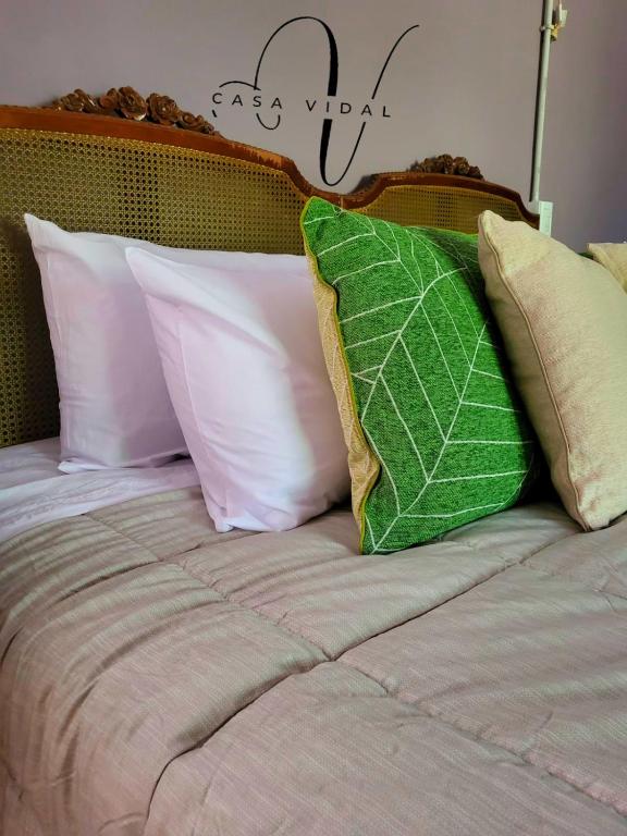 a bed with four pillows and a green leaf on it at Casa Vidal Guesthouse in Tupungato