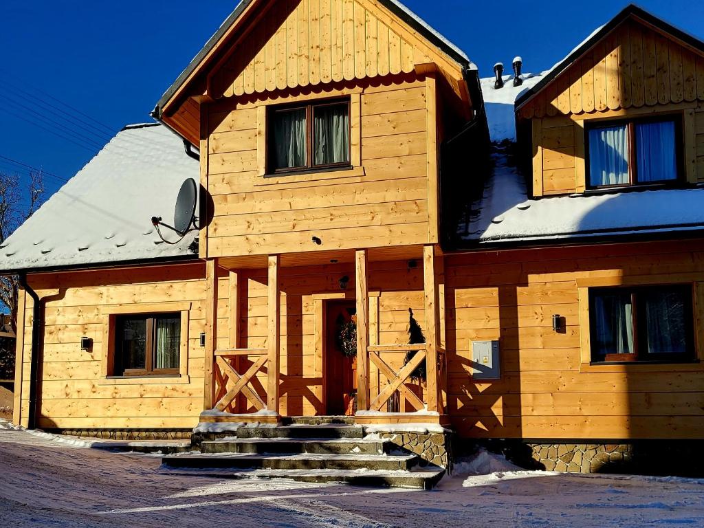 een houten huis met sneeuw erop bij Domek w Górach in Korbielów