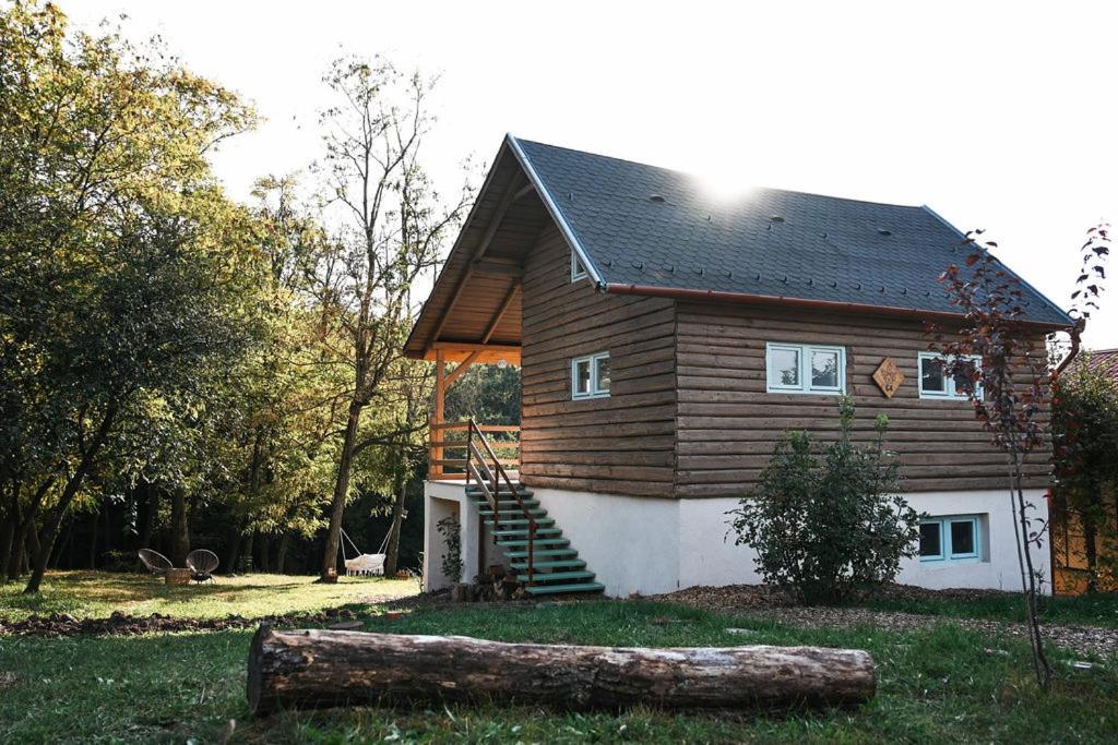 una pequeña casa con un tronco delante de ella en AvarLak, en Szurdokpüspöki