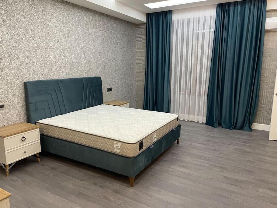 a bedroom with a bed and blue curtains at Spacious 3 bedroom with sea view in Baku