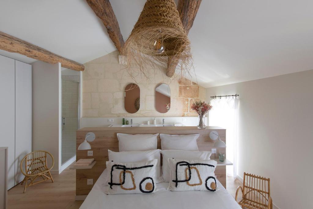 a bedroom with a bed with white sheets and pillows at MAISON V AU COEUR DU VILLAGE Alpilles in Maussane-les-Alpilles