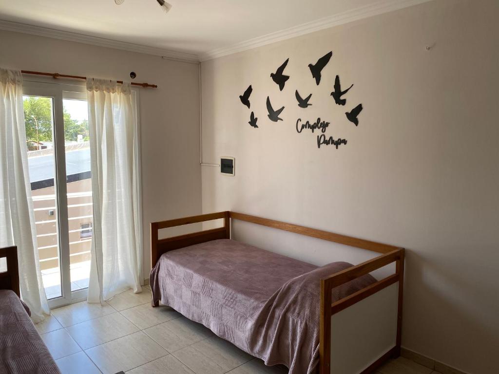 een slaapkamer met een bed met vogels aan de muur bij Complejo Pampa 1 in Santa Rosa