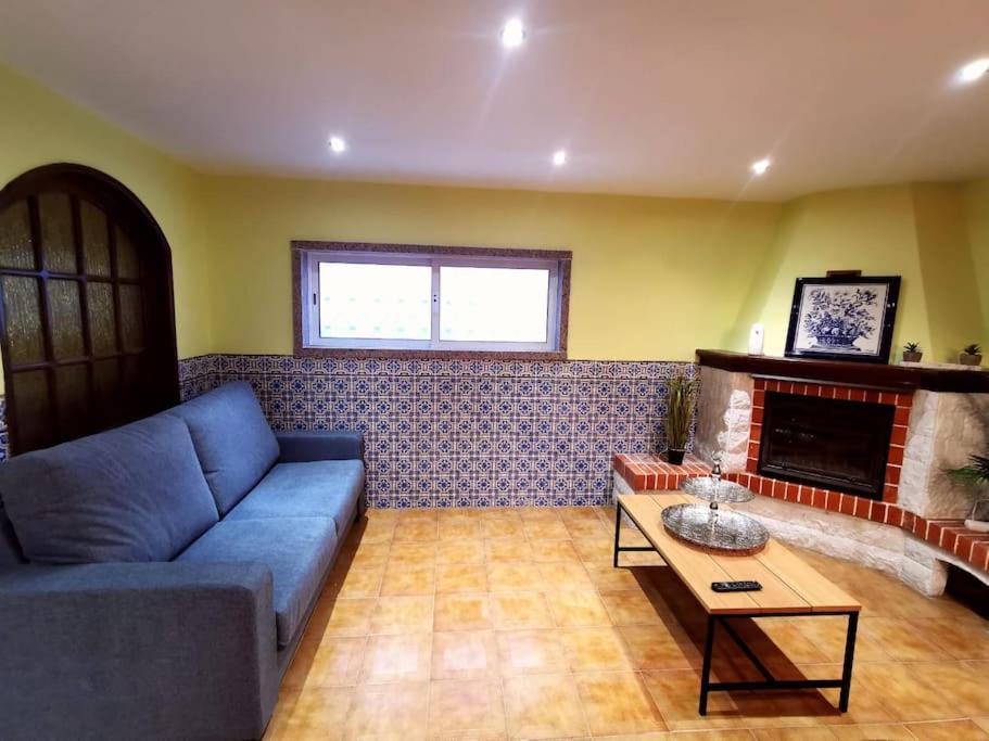 Nina23 - garagem gratuita في أفيرو: غرفة معيشة مع أريكة زرقاء ومدفأة