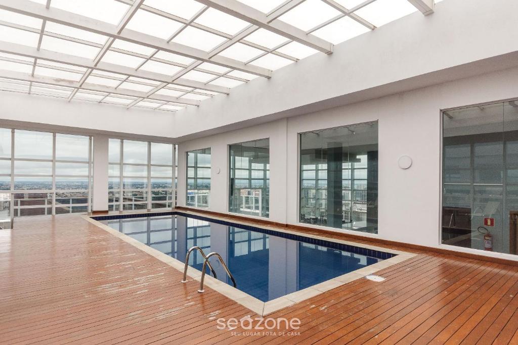 an indoor swimming pool in a building with windows at Studio cond com piscina 180m hard rock café ESR1912 in Curitiba