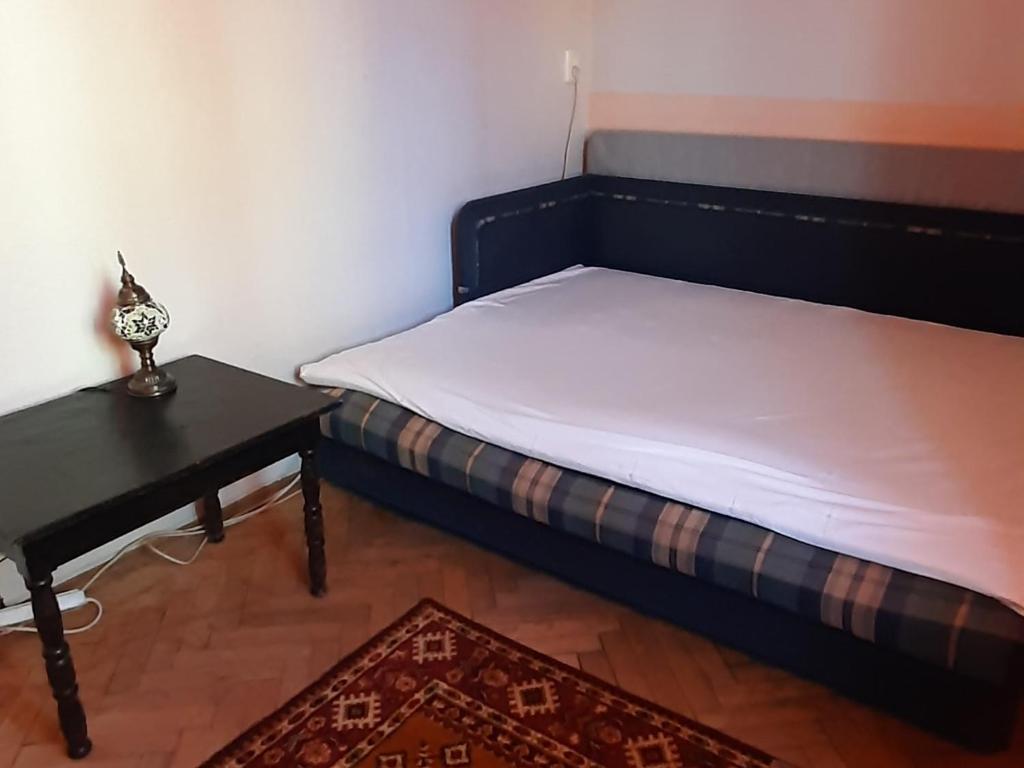 Bett in einem Zimmer mit einem Nachttisch und einem Tisch in der Unterkunft Квартира возле парка Б. Хмельницкого (центр) из первых рук in Tschernihiw