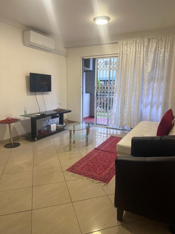 Una sala de estar con un sofá y un televisor. en DURBAN BEACH HOLIDAY HOME, en Durban